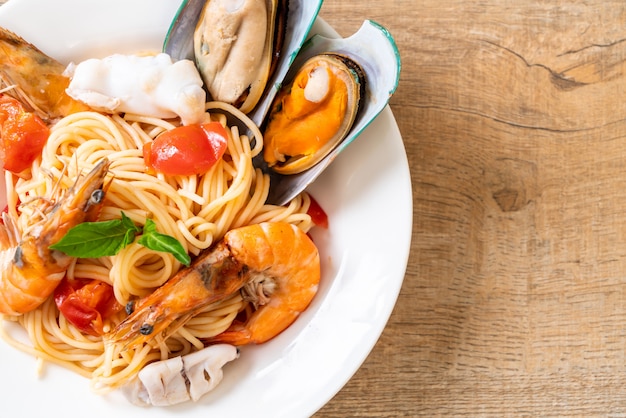 Foto spaghetti ai frutti di mare con vongole, gamberi, calamari, cozze e pomodori