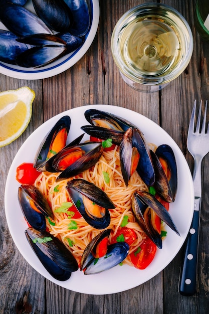 Seafood pasta spaghetti with mussels and tomatoes on wooden background