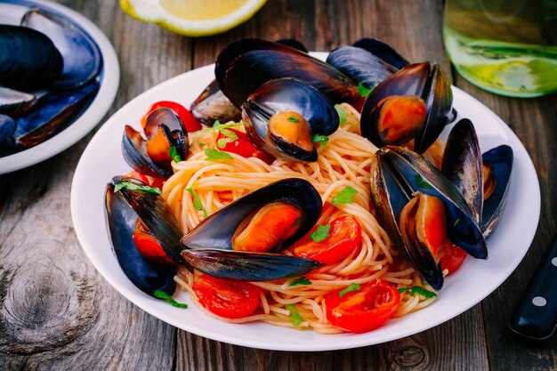 Seafood pasta spaghetti with mussels and tomatoes on wooden background