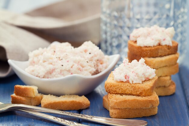 Seafood pate with toasts and glass of water on blue background