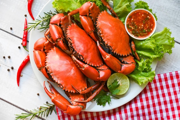 Seafood plate with herbs spices rosemary lemon lime salad\
lettuce vegetable fresh crab on white plate and seafood sauce crab\
cooking food boiled or steamed crab red in the restaurant top\
view