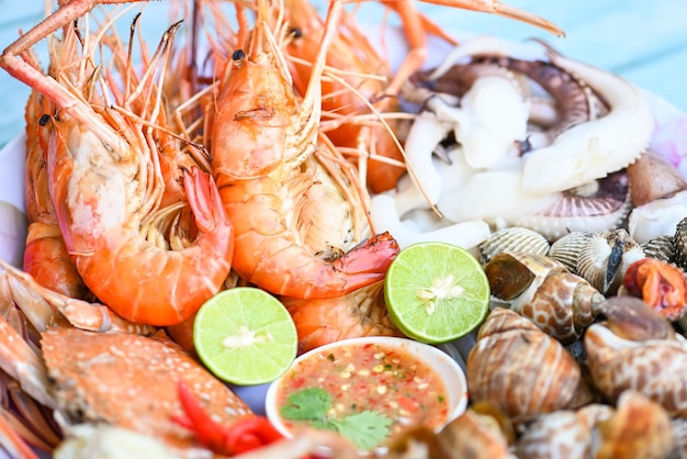 새우 조개 게 오징어 조가비와 해산물 소스 칠리 레몬 라임이 식탁에 제공되는 해산물 요리 새우 새우 해산물 뷔페 메뉴 요리 음식