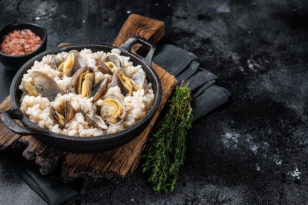 Risotto ai frutti di mare con vongole in padella backgroud nero vista dall'alto spazio di copia