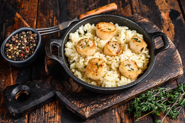 Seafood Risotto with Scallops in a pan on wooden table. Top view.