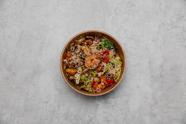 Seafood salad in a craft plate on a gray background. View from above.