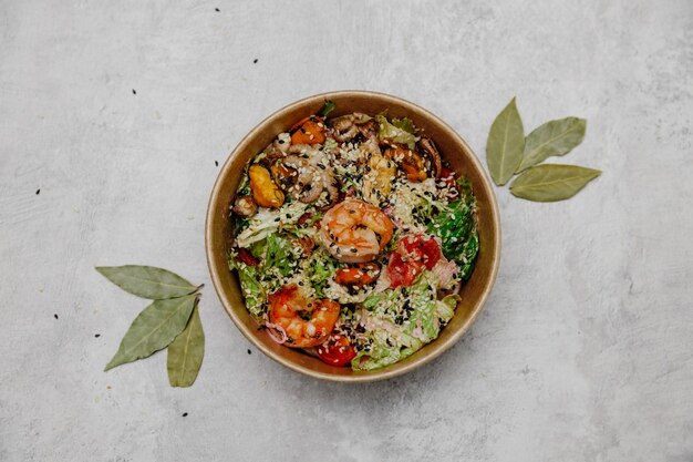 Photo seafood salad in a craft plate on a gray background. view from above.