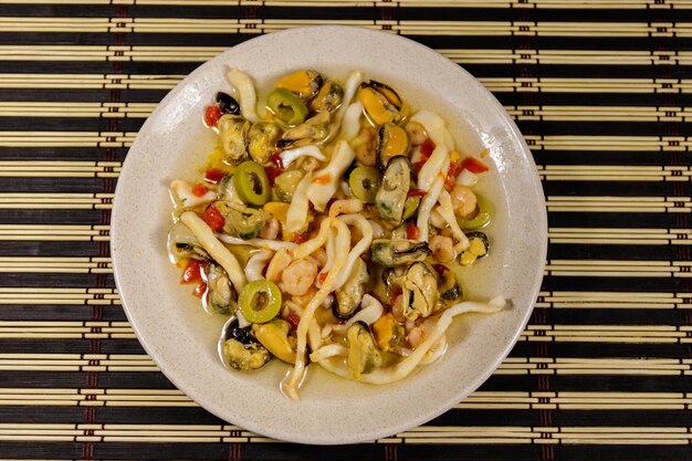 Seafood salad with shrimp, squid and mussels on bamboo mat. Top view