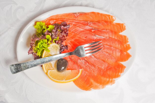 Seafood salmon garnished with fresh raw salad leaf and lemon