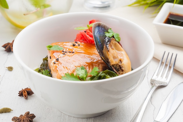 Seafood salmon steak with mussels in a white bowl