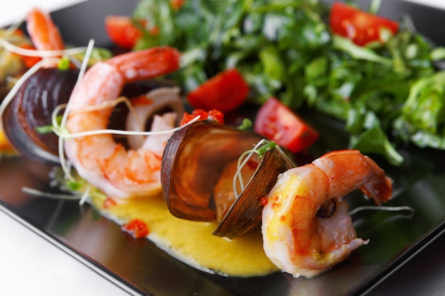 Seafood, Shrimp, Mussels, with salad on a black plate