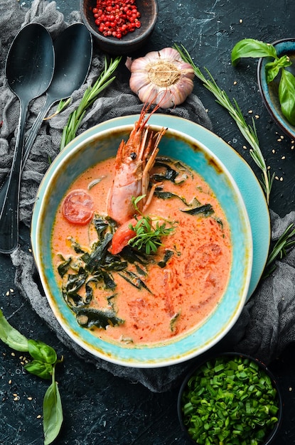 검은 돌 배경에 있는 그릇에 새우를 넣은 해산물 수프 토마토 수프 상위 뷰 소박한 스타일