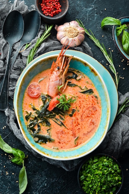 Seafood soup Tomato soup with shrimp in a bowl on a black stone background Top view Rustic style