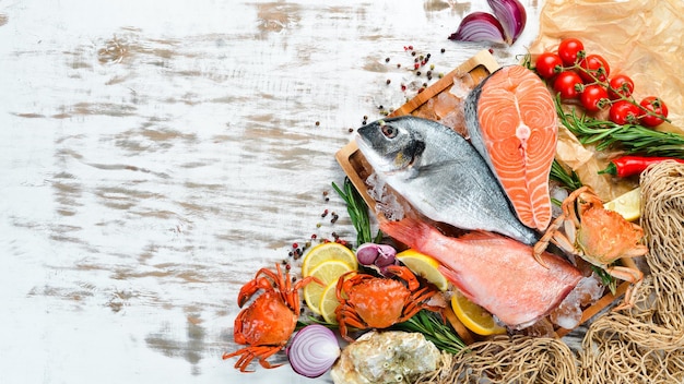 Seafood on a white wooden background: Dorado, salmon, crab, oysters. Top view. Free space for your text.