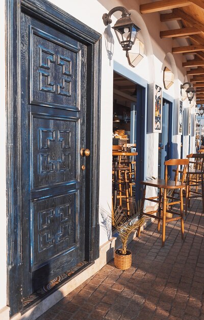 Seafront mediterranean cafe with white walls beautiful deep blue wooden doors in setting sun