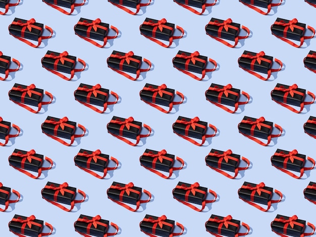 Seamless pattern made of black gift boxes tied with red ribbons on blue