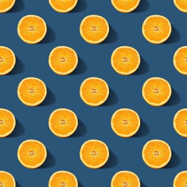 Seamless pattern of orange sliced on classic blue color background. Minimal, flat lay.