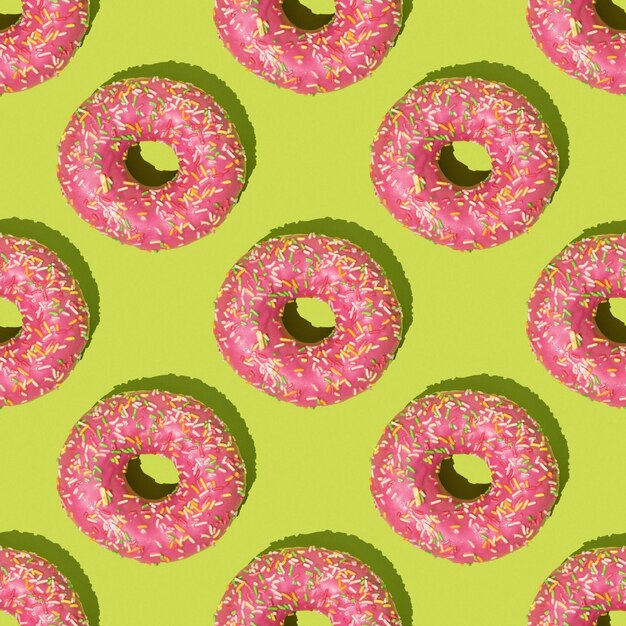 Seamless pattern of pink donuts on a green background