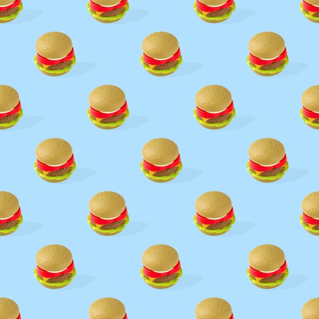 Seamless pattern of plastic childrens toy burger with salad, tomato, meat on blue background.