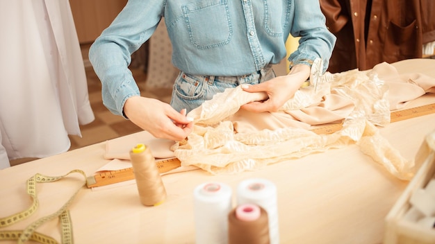 Seamstress in atelier works with beige fabric workshop manual labor small business hands