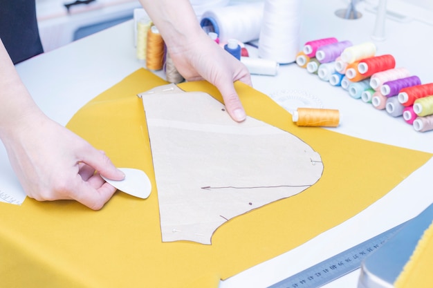 seamstress circles the pattern on the fabric close-up. A set of items for needlework: threads, needles, pins, scissors, tape measure, etc.