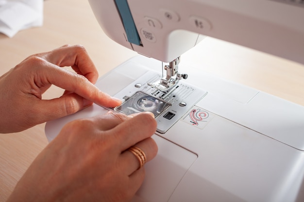 The seamstress craftsman fills the thread into the bottom spool of the automatic sewing machine