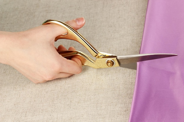 Seamstress cut purple fabric on beige fabric background