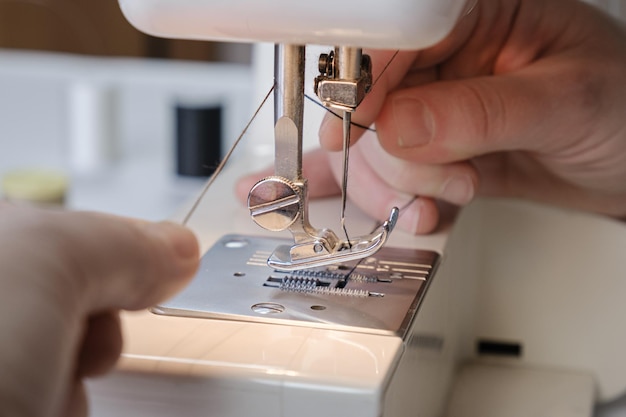 Seamstress cuts the thread on an electric sewing machine Closeup of hands Tailor workflow details