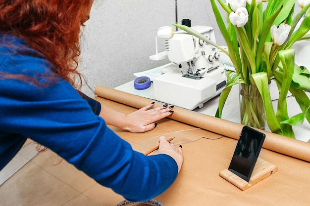 seamstress draws a pattern on kraft paper with a pencil at home business