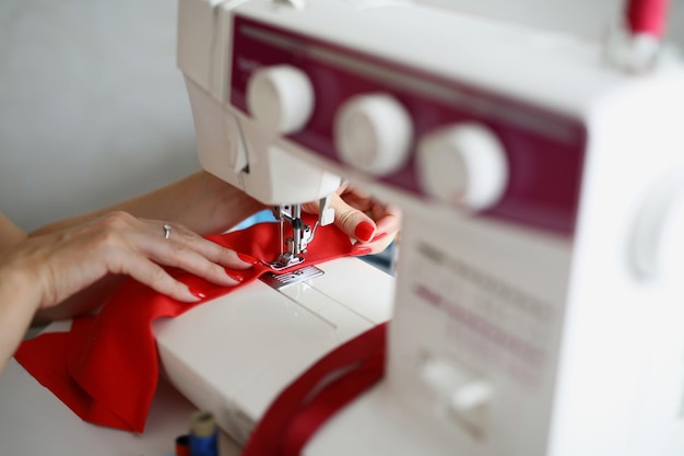 Foto le mani di una sarta cuciono una cucitura su un primo piano della macchina da cucire c'è una macchina da cucire sul
