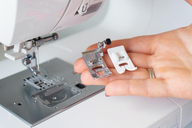 Seamstress holds sewing machine parts in hands Presser foot accessories in tailor hand Close up