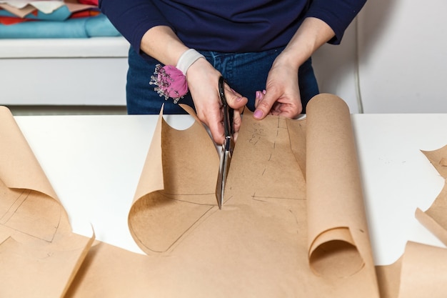 Seamstress is cutting drawing for a dress with scissors Style and design development