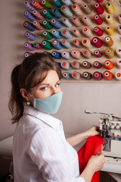 The seamstress in the mask overlays the edge of the fabric of the future red dress