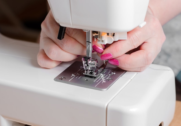 A seamstress puts the needle in the sewing machine