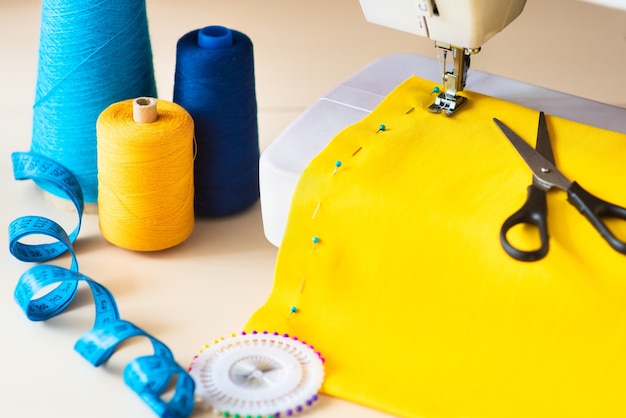 Seamstress's workplace. Professional sewing machine at work. Sewing machine sews bright textiles, meter and colored threads for sewing