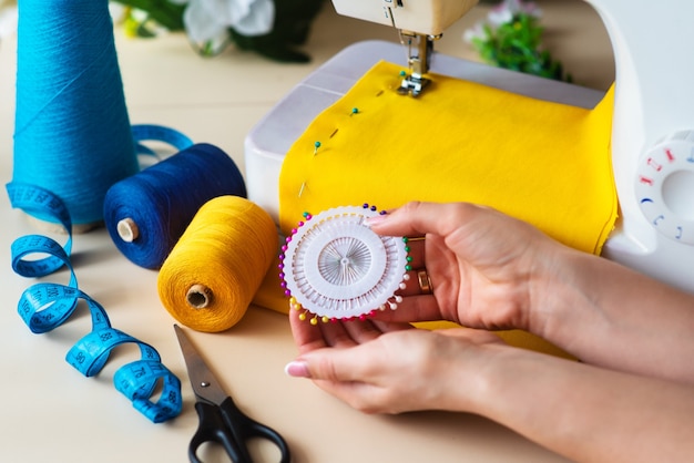 Seamstress's workplace. Professional sewing machine at work. Sewing machine sews bright textiles, meter and colored threads for sewing