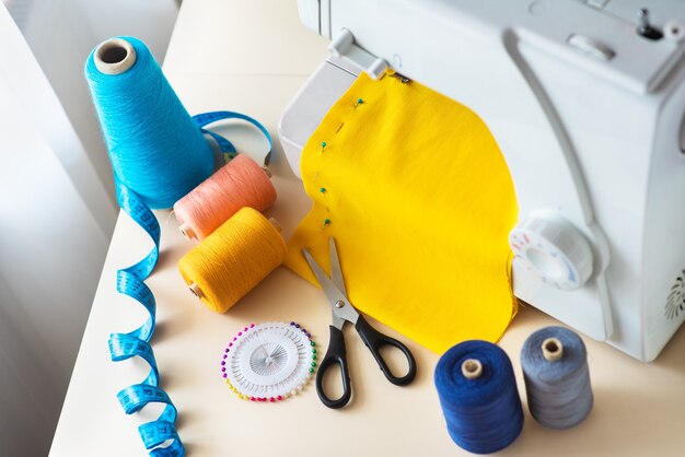 Рабочее место швеи. Профессиональная швейная машина за работой. Швейная машина шьет яркий текстиль, метровые и цветные нитки для шитья.