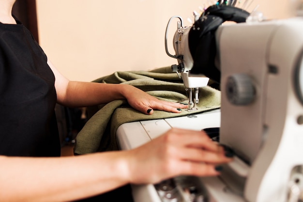 Seamstress sewing fabric on machine in workplace