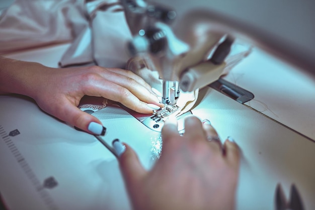 Seamstress sews clothes. Workplace of tailor - sewing machine, rolls of thread, fabric, scissors.