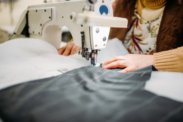 Швея сшивает ткань на швейной машине. Пошив одежды на швейной фабрике, рукоделие