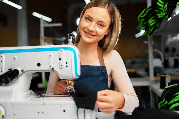 Seamstress woman at her workplace sewing clothes on sewing machine