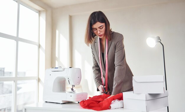 Seamstress working in the office Young woman in formal clothes is indoors Conception of style