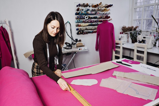 Seamstress working with sewing pattern on table in tailor shop