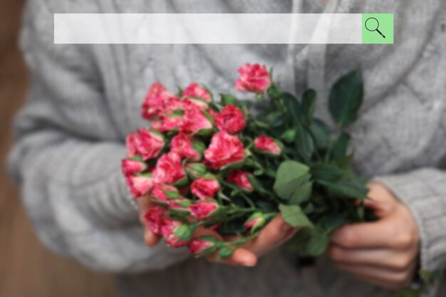 女性の手でバラの茂みのぼやけた花束の背景にある検索バー