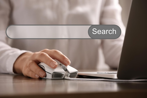 Search bar of internet browser and woman using computer mouse with laptop at table closeup