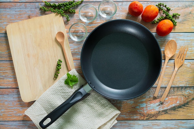 Search by image Cast iron pan and other kitchen utensils on a dark brown aged background top view