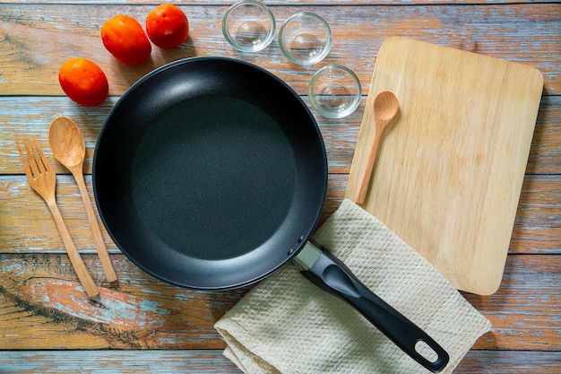 Search by image Cast iron pan and other kitchen utensils on a dark brown aged background top view