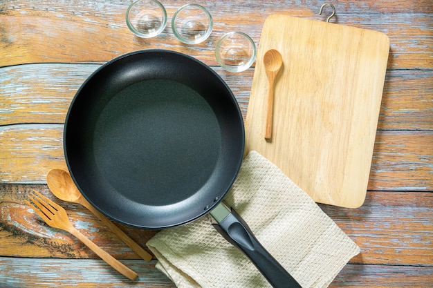 Search by image Cast iron pan and other kitchen utensils on a dark brown aged background top view