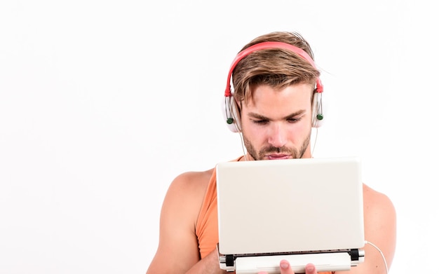 Searching for favorite music sexy muscular man listen audio man in earphones isolated on white e book unshaven man listening audio book usinf laptop and headset copy space