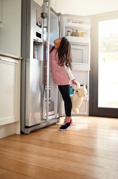 おやつを探す家の冷蔵庫で何かを探している女の子のショット