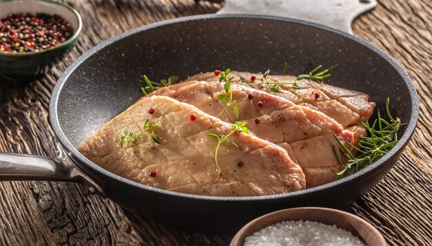 素朴な木の鍋に調味料を入れた鴨胸肉の炒め物。